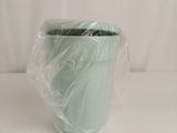 a green cup wrapped in plastic on a white table