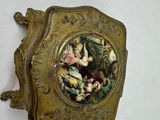 a gold plate with a painting on it hanging on a wall
