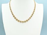 a gold chain necklace with a coin design on a mannequin