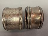 pair of silver bangles with engraved designs on them sitting on a table