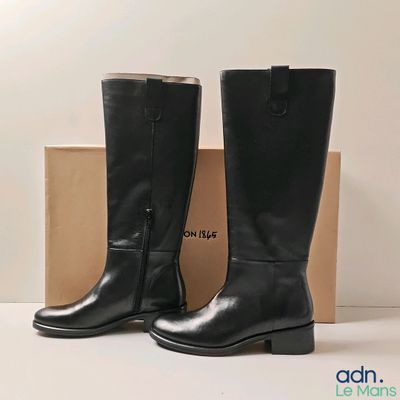 black leather boots with zippers and a box on a white surface