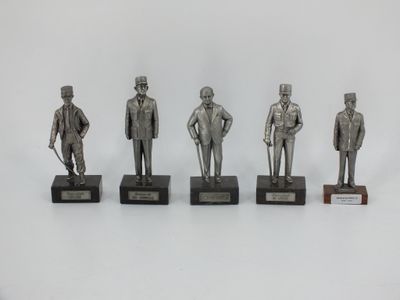 four silver statues of men in suits and hats on wooden bases