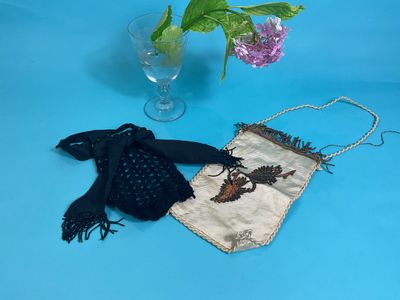 a small purse with a bird on it next to a vase of flowers