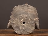 a stone sculpture of a fish head on a wooden table