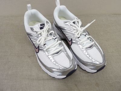 une paire de chaussures de course blanches et argentées, avec des lacets
