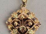 un gros plan sur un pendentif en or orné de fleurs et de feuilles