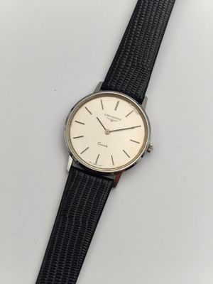gros plan d'une montre sur une surface blanche avec un bracelet noir