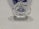 a clear glass vase with a blue lid on a white table