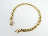 a close up of a gold bracelet on a white surface