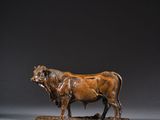 une sculpture antique en bronze représentant un taureau, posée sur un socle en bois