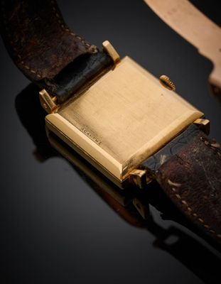un gros plan d'une montre posée sur une surface noire, avec un bracelet en cuir