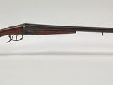 un fusil posé sur un socle transparent, devant un fond blanc