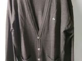 brown cardigan sweater hanging on a hanger against a white wall