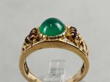 a close up of a gold ring with a green stone