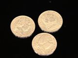 three gold coins on a black surface