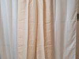 un pantalon beige suspendu à un rideau blanc devant un rideau blanc