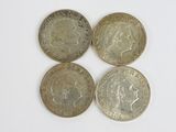 Quatre pièces de monnaie britanniques sont disposées en ligne sur une surface blanche
