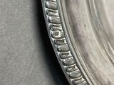 an antique silver plate with a decorative edge on a table