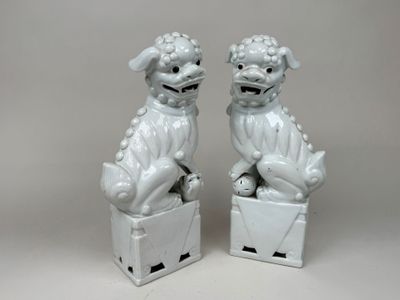 une paire de figurines blanches « foo foo foo » posées sur une boîte
