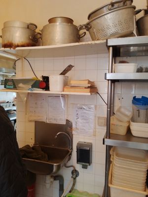 un homme debout dans une cuisine, avec des casseroles et des poêles sur les étagères