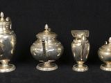three silver vases with lids and lids on a black background