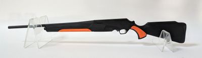 un fusil noir muni d'une poignée orange, posé sur un socle transparent