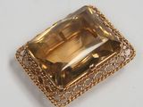 a close up of a gold plated broochle on a white surface