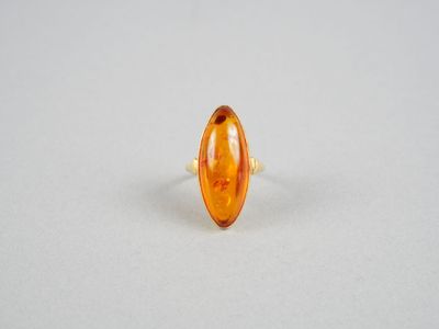 une bague ovale en verre ambré ornée d'une bande dorée