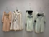 trois robes accrochées à un mur dans une vitrine de musée