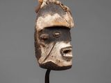 a wooden mask on a stand with a gray background
