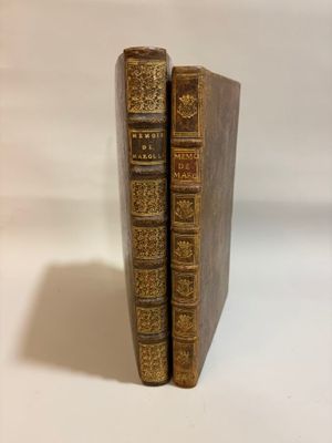 two old books sitting on top of each other on a white surface