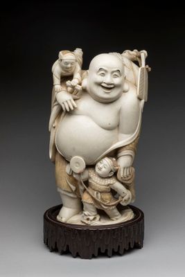 an ivory figurine of a laughing buddha holding a baby