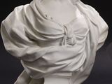 white marble bust of a woman with a shaw around her neck