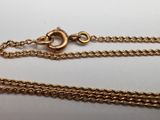 a close up of two gold chains on a white surface