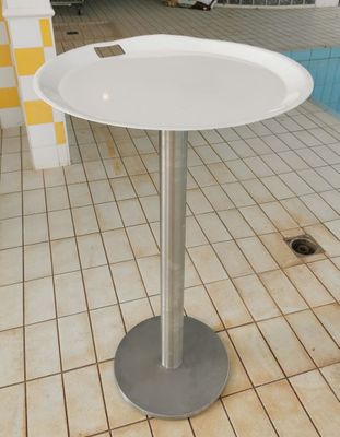 a white table with a silver base on a tiled floor