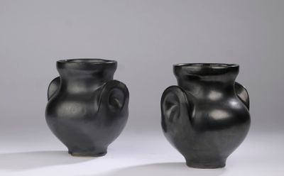 pair of black vases sitting on top of a white surface
