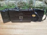 two black purses sitting on top of a wooden table next to a stone wall