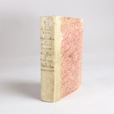 un vieux livre posé sur une table blanche à côté d'un mur blanc