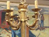a gold chandelier hanging from a ceiling with a painting in the background