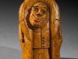 l'image d'une statue en bois représentant un homme coiffé d'un chapeau