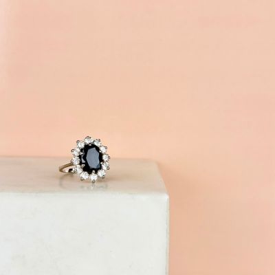 a close up of a black and white diamond ring on top of a marble block
