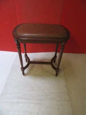 a small table with a brown leather top on a white floor