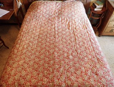 un lit recouvert d'une couette rouge et blanche dans une chambre à coucher