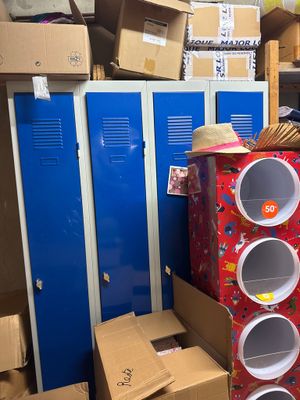 une pile de cartons et de boîtes dans une pièce équipée de casiers bleus