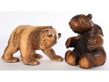 une paire d'ours en bois sculptés assis l'un à côté de l'autre sur une surface blanche