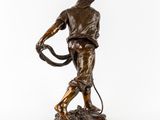 a bronze statue of a man with a whip on a white background
