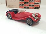 a red toy car sitting on a table next to a box