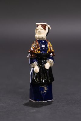 une petite figurine représentant une femme en robe et avec un chapeau