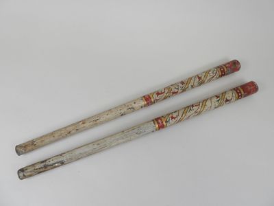 deux vieilles baguettes en bois posées sur une surface blanche