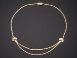 a gold chain necklace with two small hearts on a black background